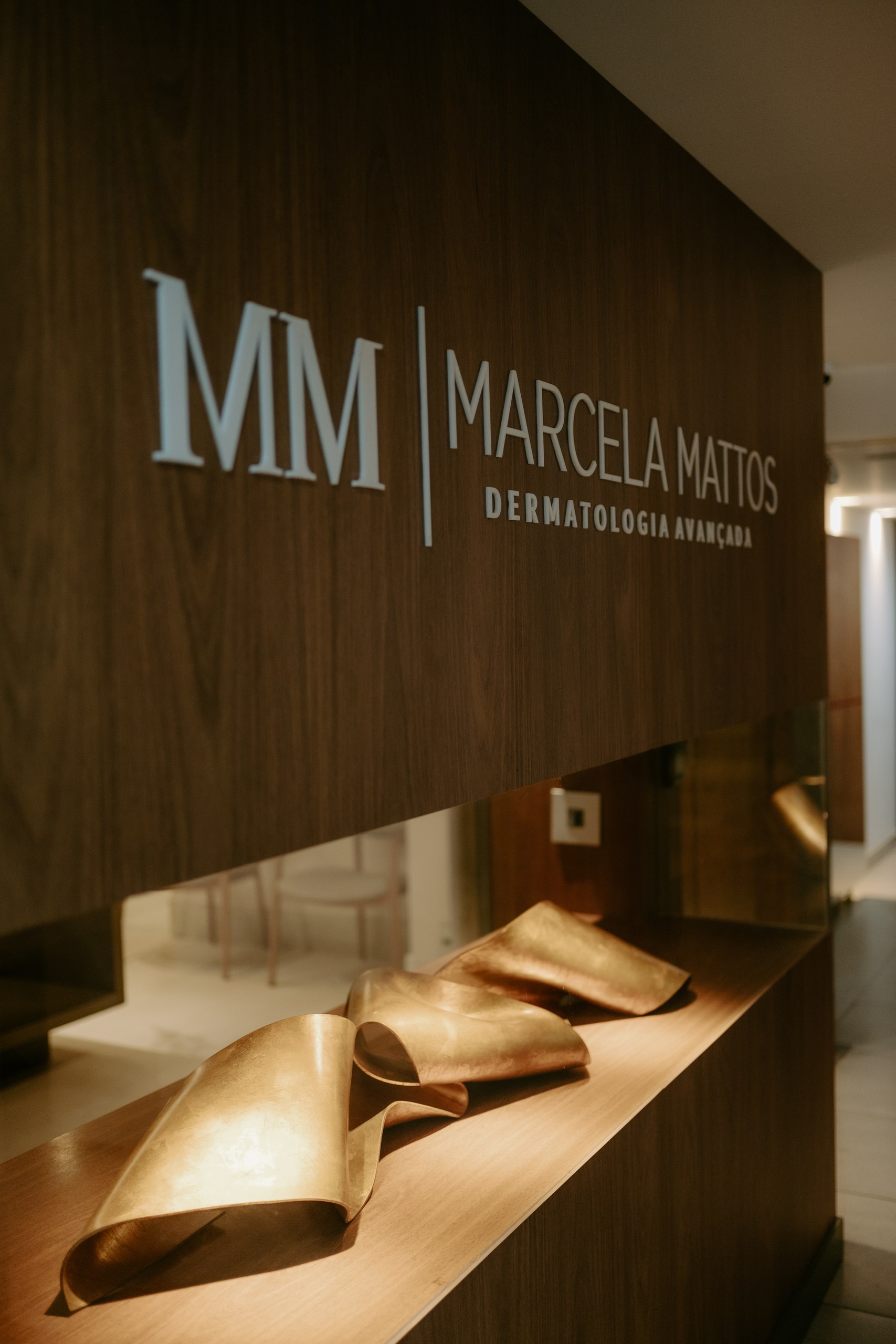 Detalhe do letreiro Marcela Mattos Dermatologia Avançada sobre painel de madeira