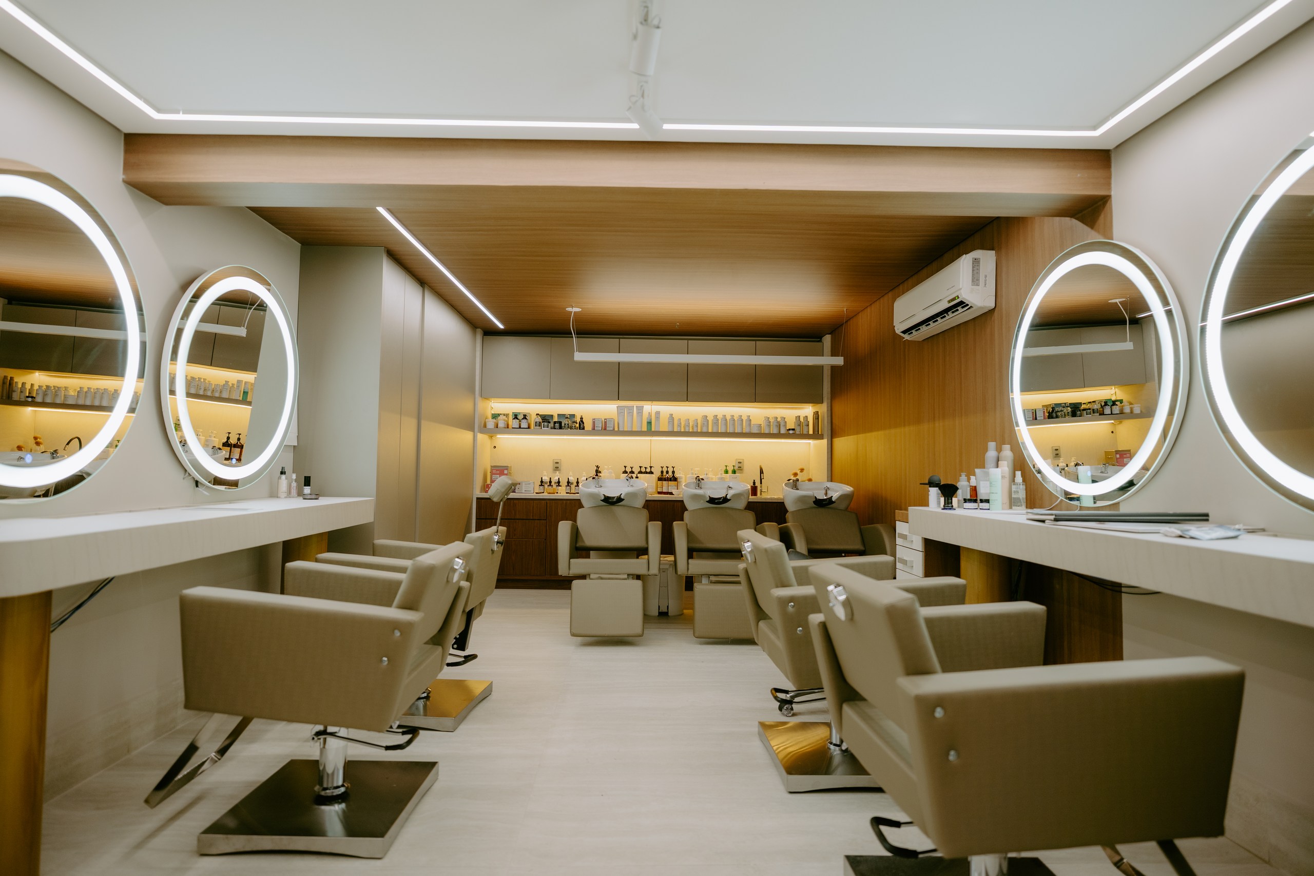 Vista geral do salão DOM Hair, com bancadas, espelhos iluminados e cadeiras de atendimento
