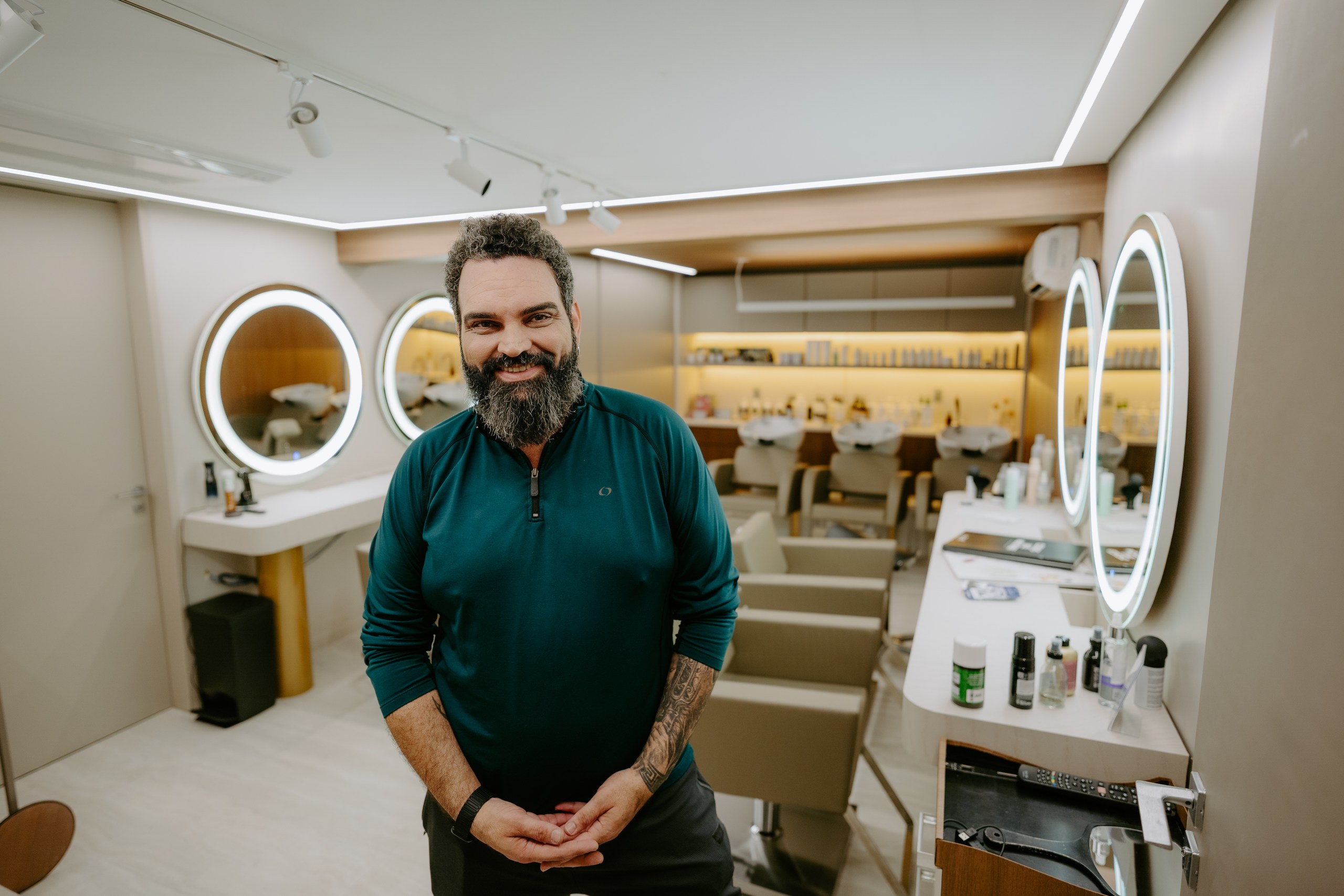 Felipe Messias no salão DOM Hair, com espelhos iluminados e bancadas ao fundo